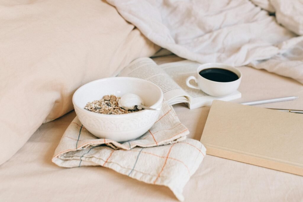 A bedside table with a notebook, pen, book, and warm lamp light