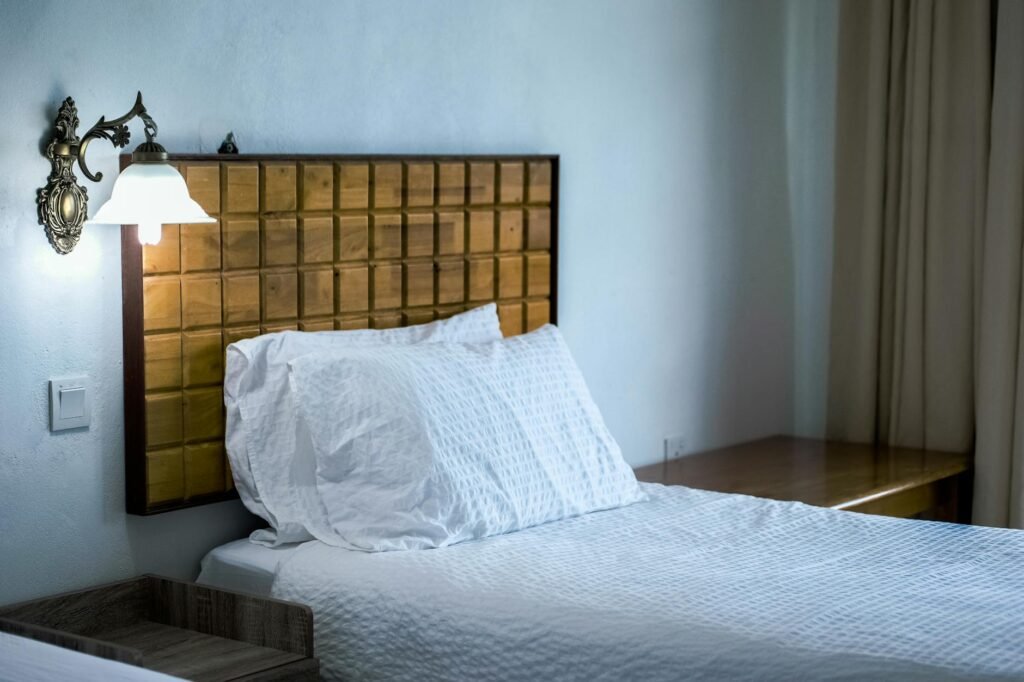 A nightstand with a notebook, pen, and phone charging away from the pillow