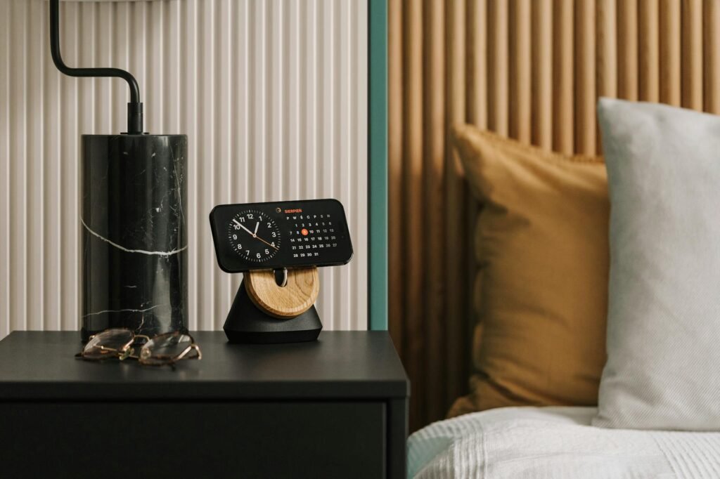 A sleep diary notebook and clock on a bedside table