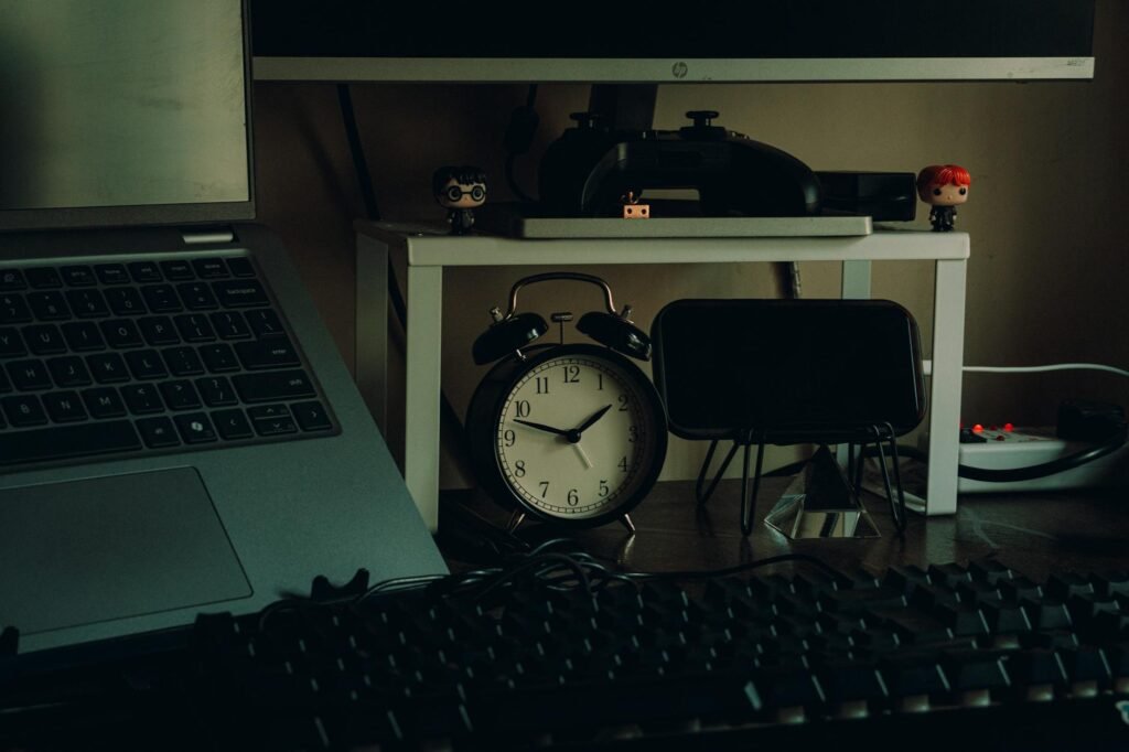 An iced coffee on a desk next to a laptop and a clock showing late afternoon.
