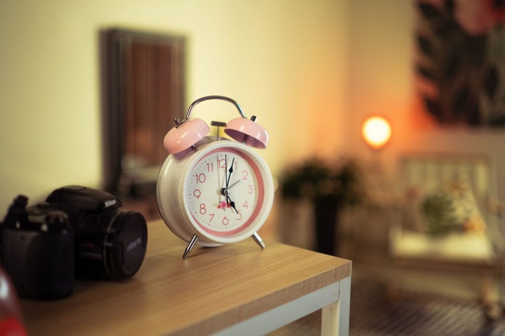 A bedside table with an analog alarm clock, a book, and no glowing phone screen