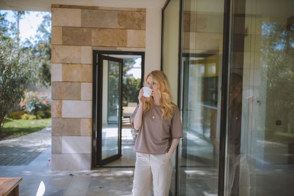 An adult standing outside with a mug in soft morning light before work