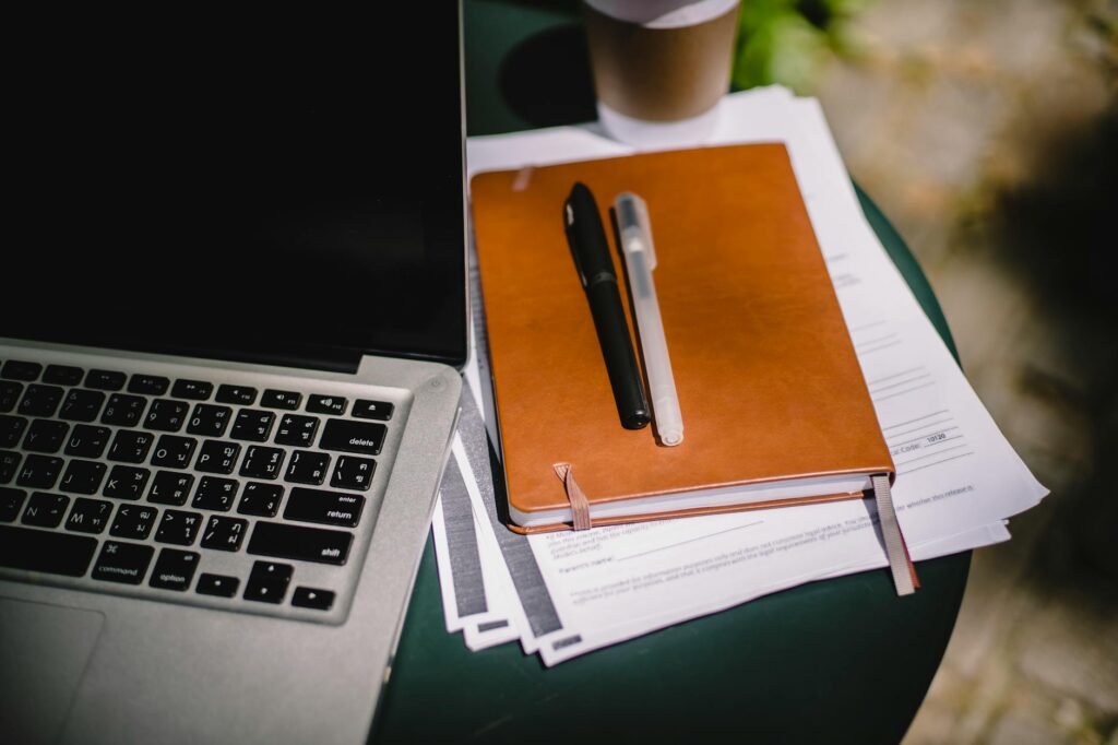 A closed laptop and planner on a softly lit desk in the evening
