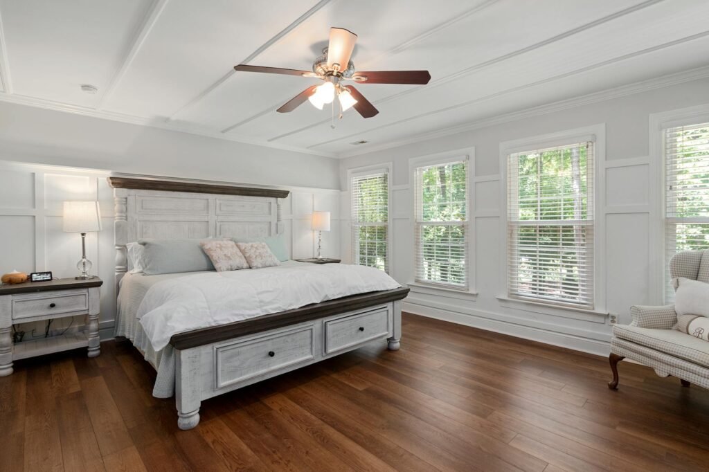 A simple bedroom setup with a fan, eye mask, and uncluttered nightstand.