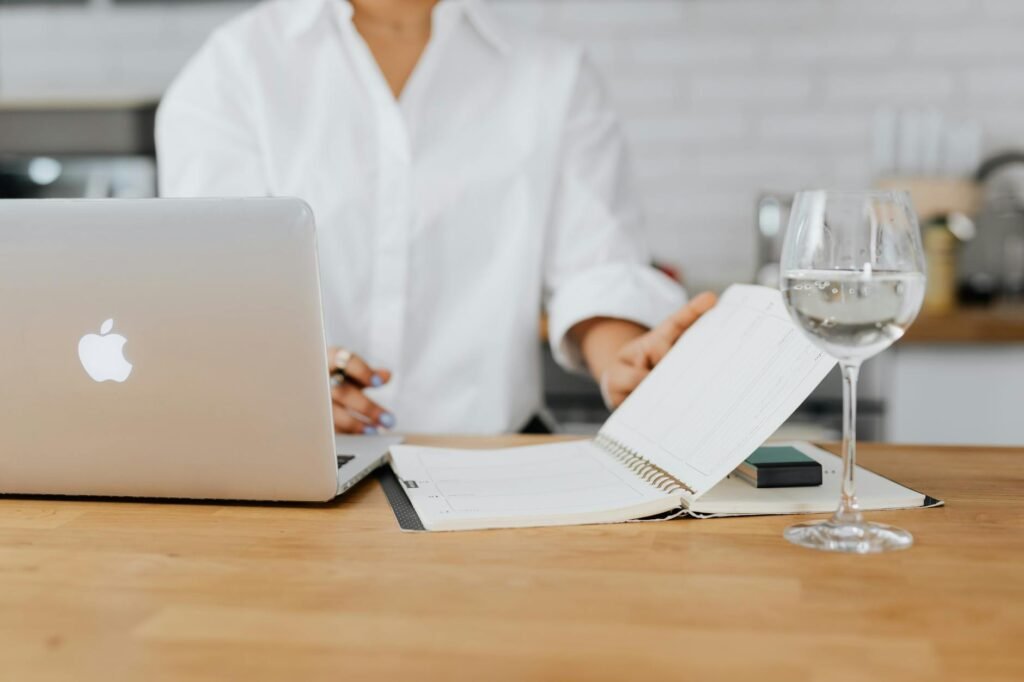 A closed laptop beside a planner and a glass of water on a tidy desk