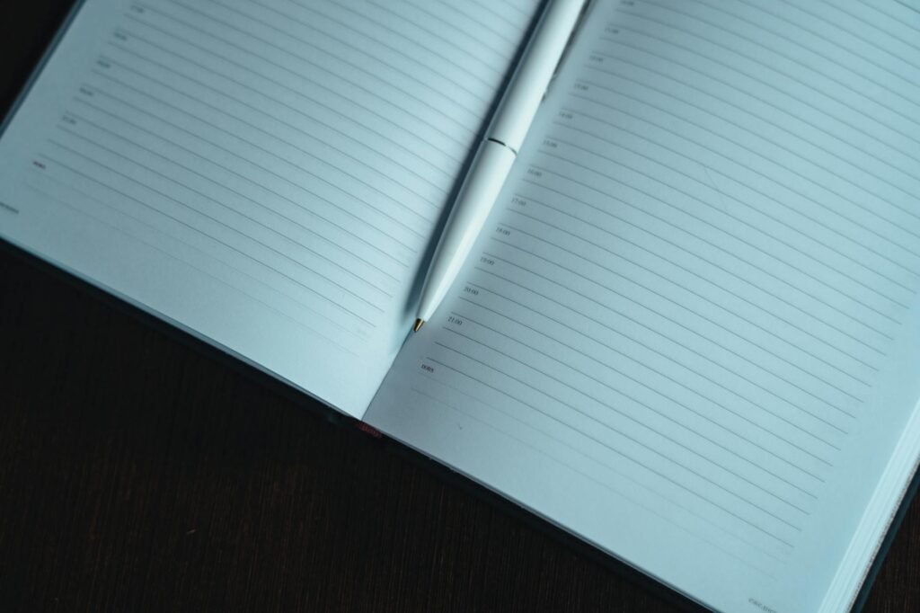 A paper sleep diary and pen on an organized bedside table