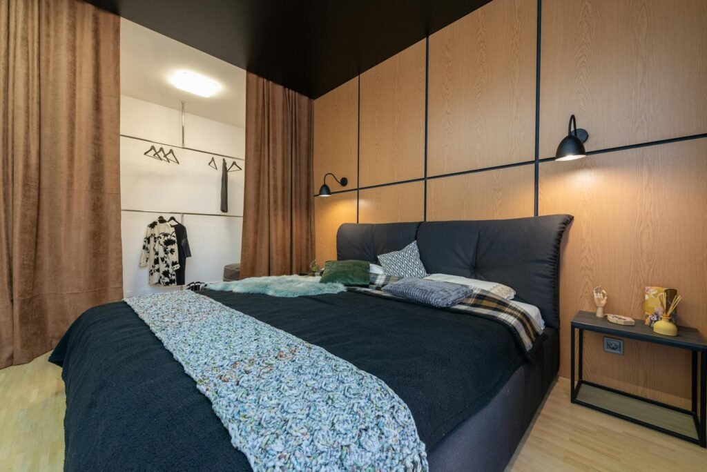 A dark, tidy bedroom with blackout curtains and a small bedside lamp