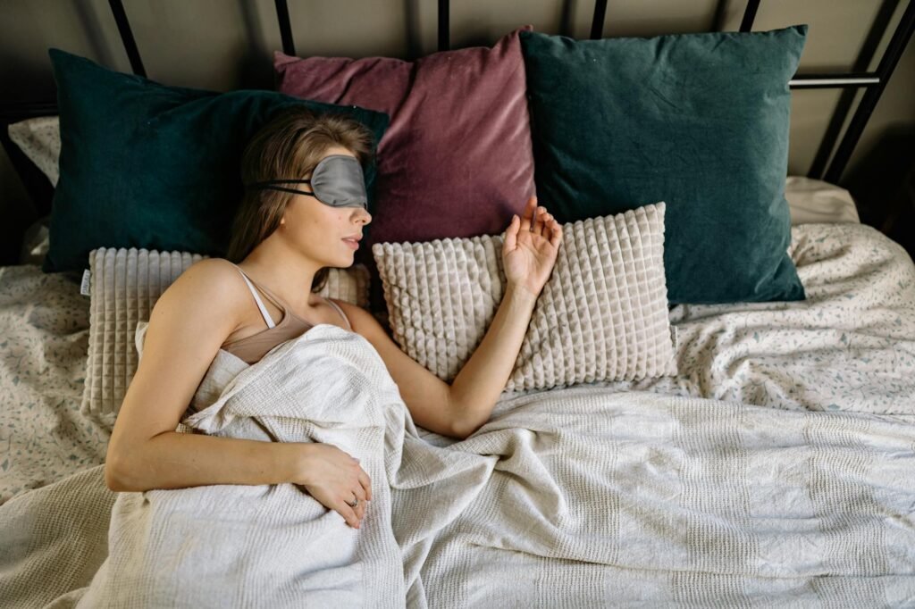 A tidy nightstand with an eye mask, small fan, and notebook