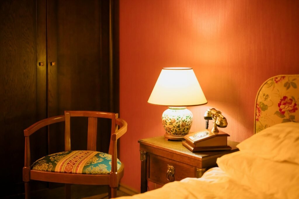 A dim bedroom with a notebook on the dresser and a phone charging outside the sleeping area