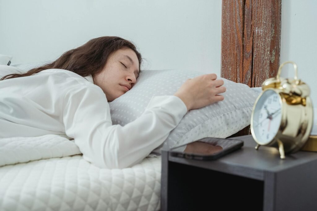 A tidy bedside table with an alarm clock, a book, and soft lighting