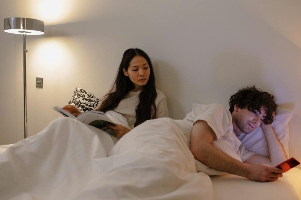 A smartphone charging on a table outside a bedroom at night.