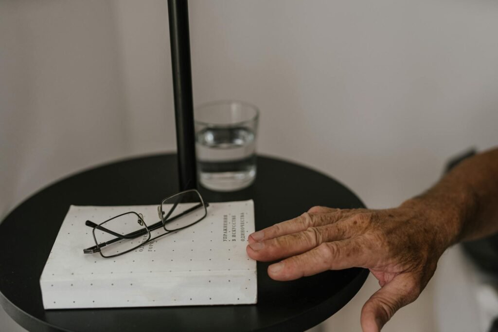 A bedside table with a book, a glass of water, and a warm lamp.