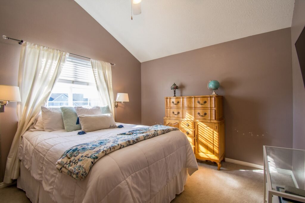 A tidy bedroom with a clear dresser top and uncluttered floor beside the bed