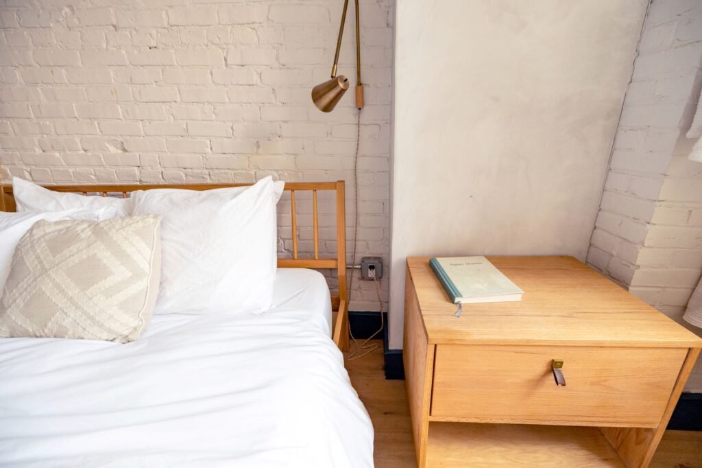 A simple bedroom nightstand with only a lamp, book, and water glass