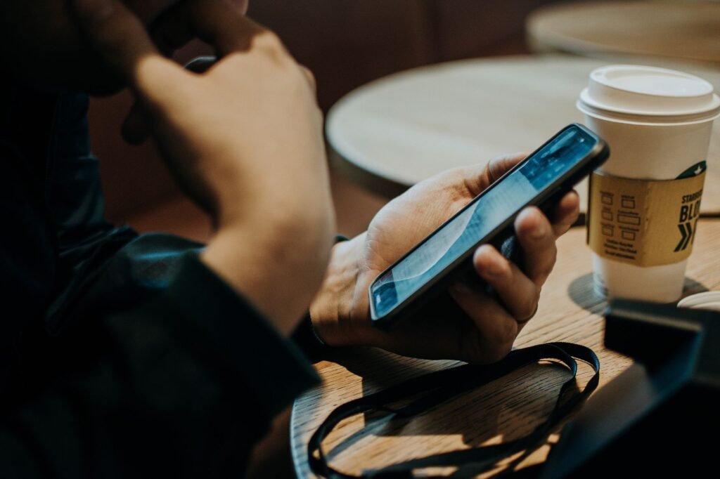 Receipts, a takeaway coffee cup, and a phone alarm on a kitchen table.