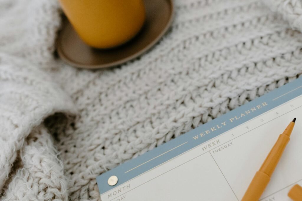 A weekly planner on a desk with wake times written in and a coffee mug nearby.