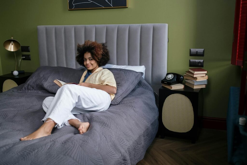 A nightstand with a low lamp, a book, and a phone turned face down before bed.